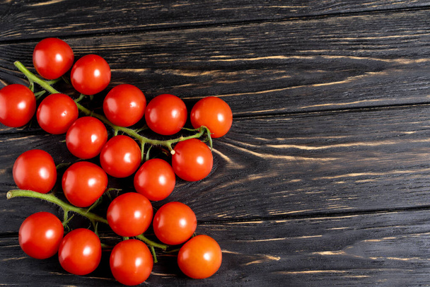 Cherry tomatoes on the dark wooden table. Juicy ripe vegetables on a black background. Healthy eating. vegetarian food - Zdjęcie, obraz