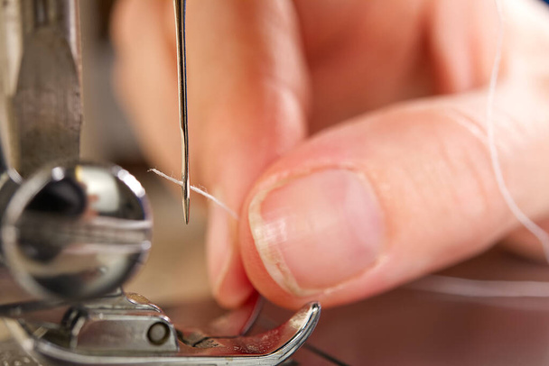 mulher enfiando uma agulha em uma máquina de costura. close up, foco seletivo
. - Foto, Imagem
