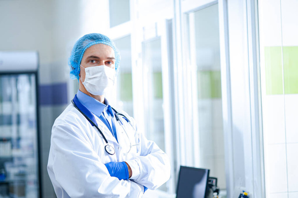 Врач в защитной маске с фонендоскопом стоит в больнице. Концепция здоровья. Эпидемия коронавируса - Фото, изображение
