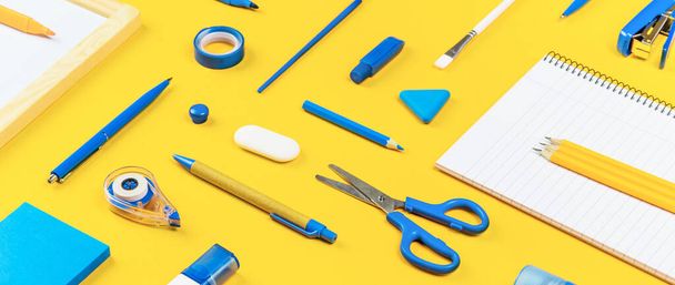 Assorted office and school white and blue stationery on bright yellow background. Organized knolling for back to school or education and craft concept. Selective focus. Banner - Photo, Image