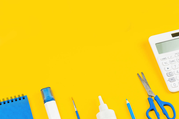 Assorted office and school white and blue stationery on bright yellow background. Organized knolling for back to school or education and craft concept. Selective focus. Copy space - Photo, Image