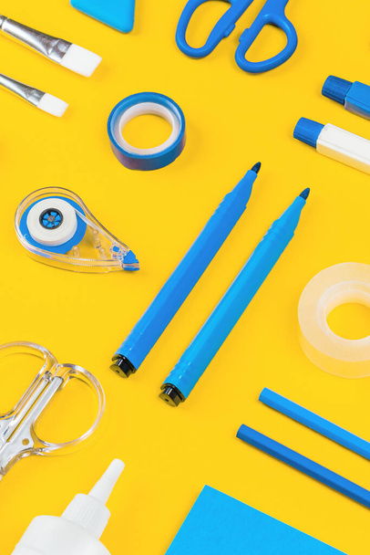 Assorted office and school white and blue stationery on bright yellow background. Organized knolling for back to school or education and craft concept. Selective focus - Zdjęcie, obraz