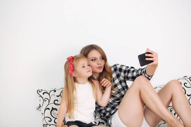 mom and daughter taking selfie while resting on bed at home - Photo, image