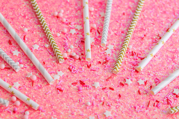 Drink straws and shiny holiday decorations close-up, pink background for party - Photo, Image