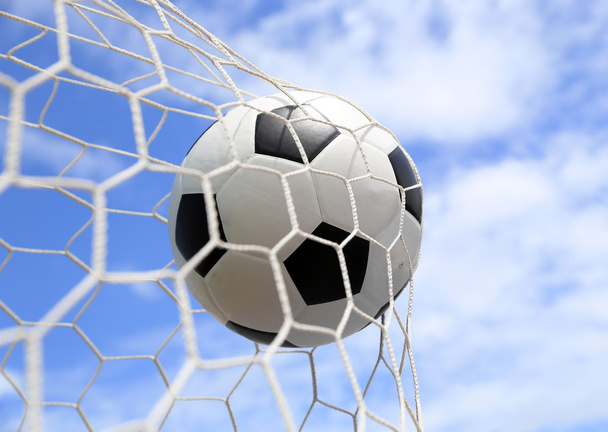Футбольный мяч в сетке на голубом небе
 - Фото, изображение