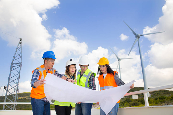 Genç mühendisler ve işçiler rüzgar çiftliğinde toplantı yapıyorlar. - Fotoğraf, Görsel