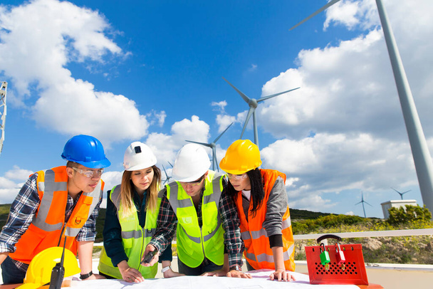 Jonge ingenieurs en werknemers hebben een bijeenkomst op windmolenpark - Foto, afbeelding