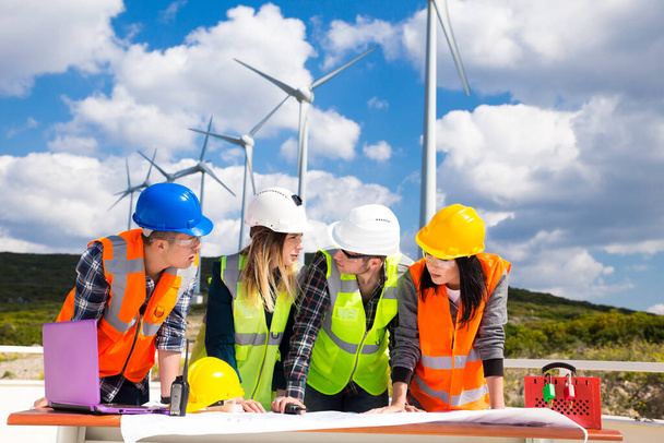 Молодые инженеры и рабочие встречаются на ветряной электростанции - Фото, изображение