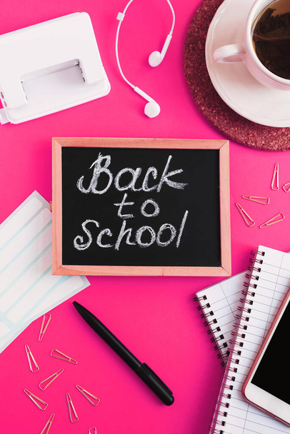 Quadro negro com texto escrito "De volta à escola", chá verde e artigos de papelaria escolar sobre fundo rosa. Conceito de ensino secundário
 - Foto, Imagem