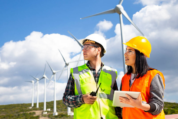 Jovens trabalhadores que procuram e verificam turbinas eólicas no campo
 - Foto, Imagem