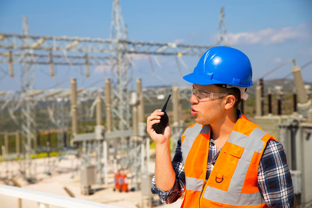Empresario usando walkie-talkie contra planta de energía - Foto, Imagen