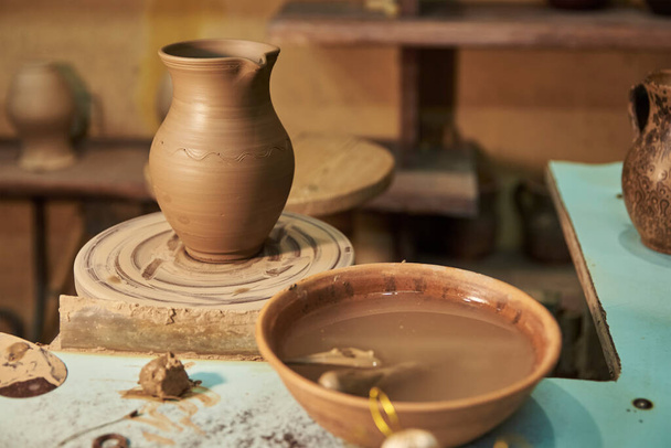 Clay pot on a potter's wheel in workshop interior - Photo, Image