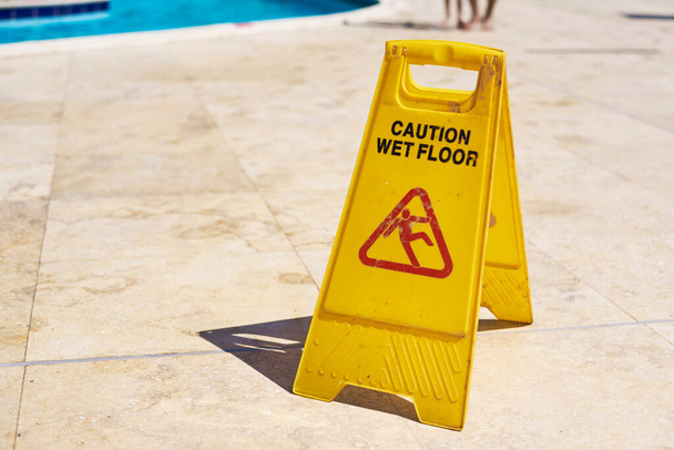 Yellow wet floor caution sign in summer day, close up - Photo, Image
