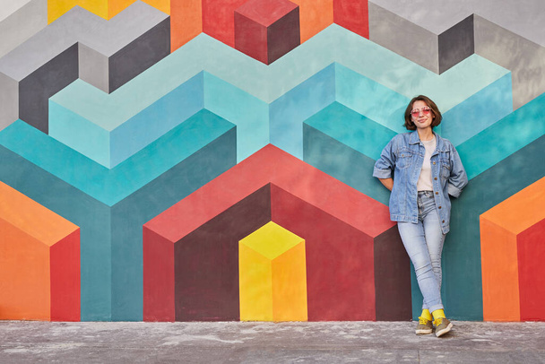 Happy woman leaning on colorful wall - Фото, зображення
