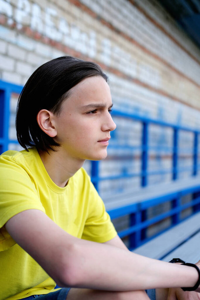 Oldalnézet portré egy elmélkedő tinédzser fiúról. Tinédzser, aki a stadion lépcsőjén ül. gondolkodás probléma vagy gondolkodás, szorongó melankolikus srác komoly arc úgy érzi, magányos vagy kétséges és aggódik. - Fotó, kép