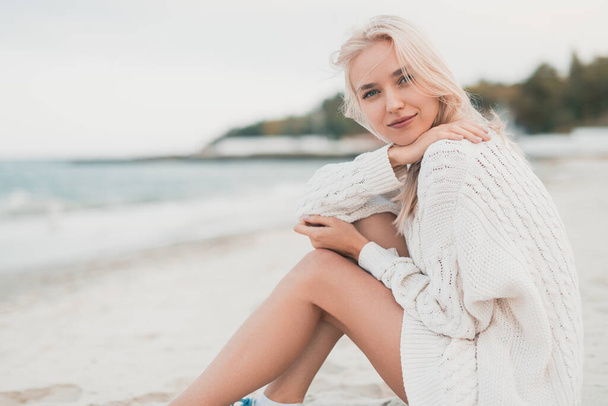 Young woman in sweater resting on seashore - Фото, зображення