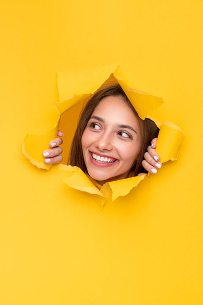 Szczęśliwa młoda kobieta podglądająca z dziury w papierze - Zdjęcie, obraz