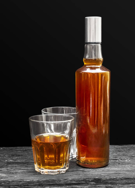 Egy üveg whisky, két pohárral, fekete háttérrel. Közelről.. - Fotó, kép