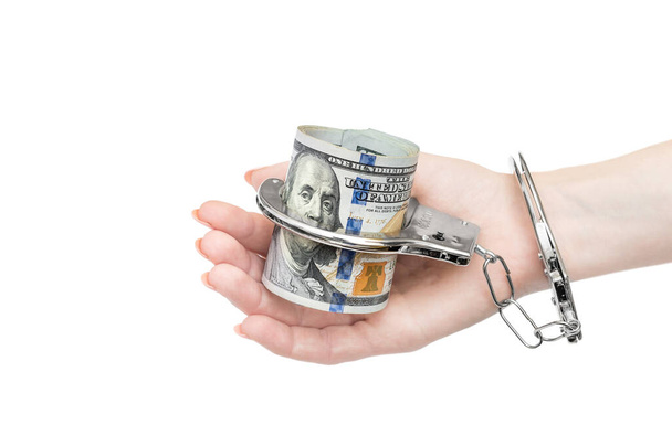 Рука жінки тримає гроші, які прикуті наручниками. Ізольовані на білому
. - Фото, зображення
