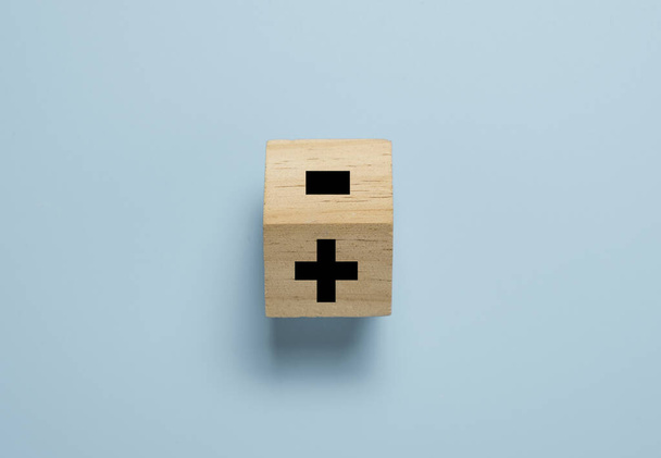 Bloc de cube en bois qui glisse pour changer le signe moins en signe plus sur fond bleu. Pensée positive et concept de mentalité. - Photo, image