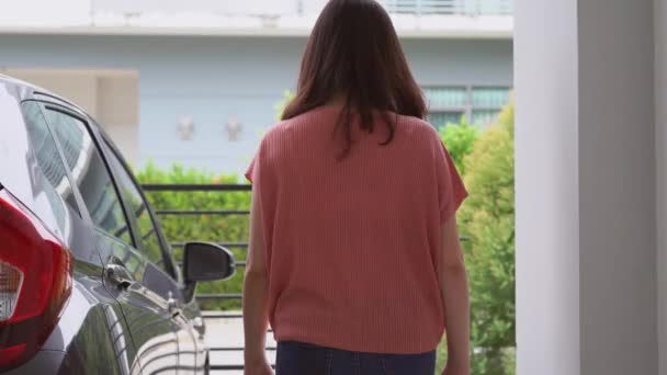 Beautiful Asian woman walking to her car and get in a car at her home. Safe driving concept. - Materiał filmowy, wideo
