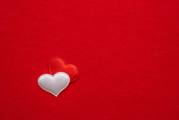 バレンタインデーカードのフラットトップビューをレイアウトします。2つの小さな繊維の心、白と赤、近くの赤いベルベットの紙の背景にあります。結婚式のコンセプトが好き。テキストのスペースをコピー - 写真・画像