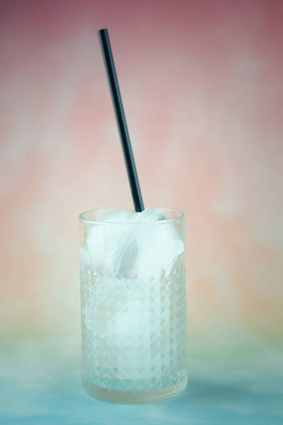 Порожнє скло з кубиками льоду та чорною соломою в склі, готовому до пиття
 - Фото, зображення
