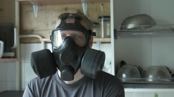 Человек в противогазе сидит дома на кухне. химическое оружие, защита от вирусов - Кадры, видео