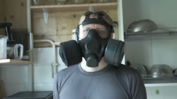 Gaz maskeli adam evde mutfakta oturuyor. Kimyasal silah, virüs koruması - Video, Çekim