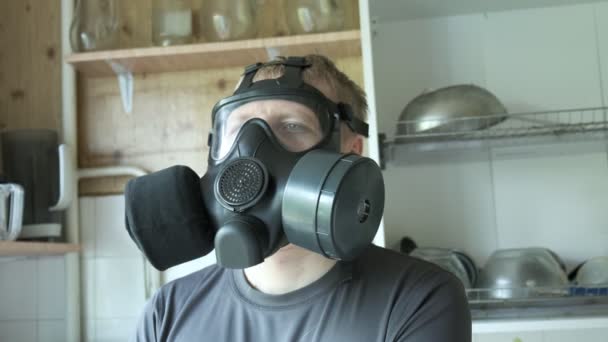 Mann mit Gasmaske sitzt zu Hause in der Küche. Chemiewaffen, Virenschutz - Filmmaterial, Video