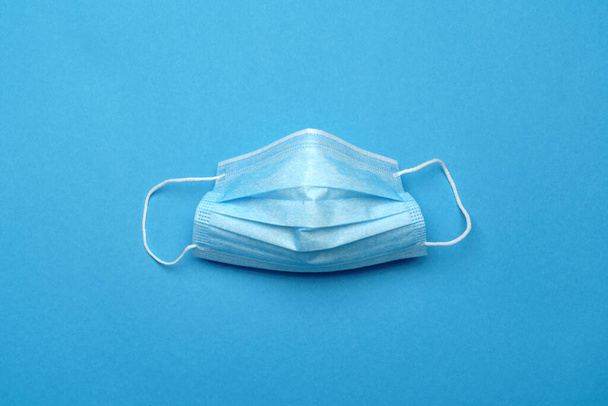 Disposable blue medical face mask on blue background - Photo, Image