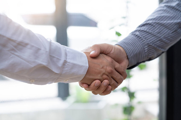 Dos hombres de negocios seguros estrechando manos durante una reunión en la oficina, el éxito, el trato, el saludo y el concepto de socio. - Foto, imagen