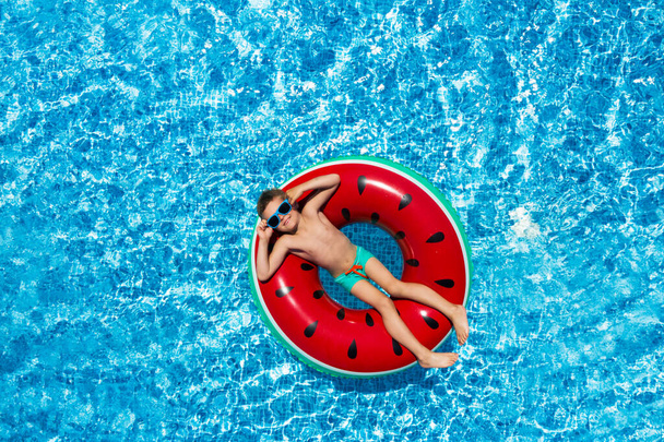 Cute little boy with inflatable ring in swimming pool, top view. Summer vacation - Valokuva, kuva