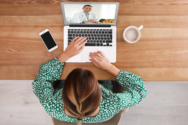 Woman using laptop for online consultation with nutritionist via video chat, top view - Фото, зображення