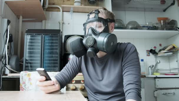 hombre irritado en máscara de gas habla smartphone en la cocina en casa. protección contra el virus
 - Metraje, vídeo