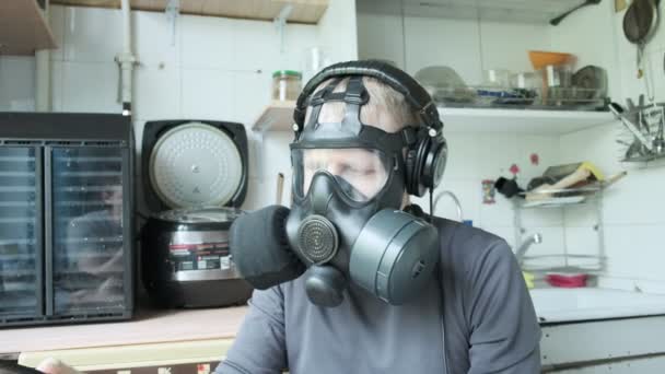 Mies kaasunaamarissa kuuntelee musiikkia kuulokkeissa, pudistaa päätä. epidemia kotona - Materiaali, video