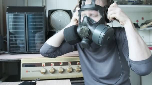 Człowiek w masce gazowej słucha muzyki w słuchawkach, potrząsa głową. epidemia w domu - Materiał filmowy, wideo