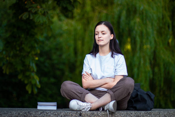Egy lány meditál a Lótusz pozícióban a friss levegőn a parkban. A lány jóga után ellazul. Visszapillantás, szöveghely - Fotó, kép