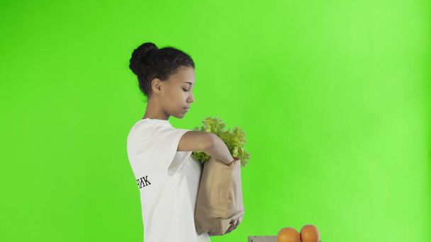 Bolsa de papel de carga mujer feliz con verduras y frutas orgánicas saludables sobre fondo de croma key
 - Foto, Imagen