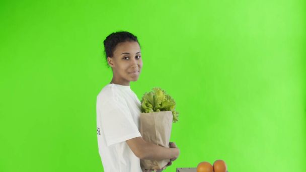 Счастливая женщина загрузить бумажный пакет с органическими здоровыми овощами и фруктами на хрома ключевых фоне - Фото, изображение
