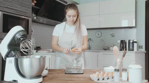 料理人の女性は卵を割っている。ケーキ料理 - 写真・画像