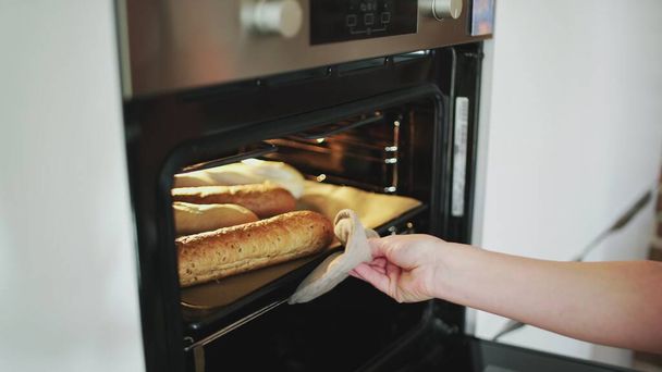Een vrouwtje zet brood in de oven. - Foto, afbeelding