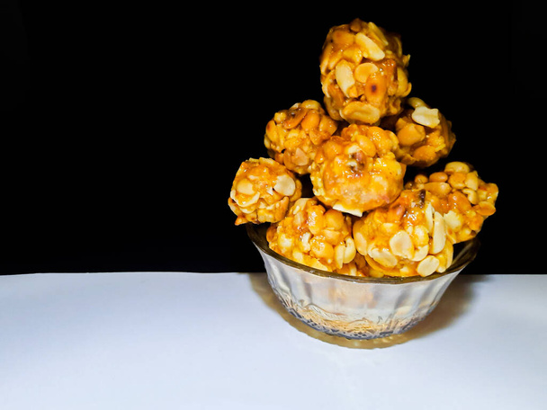 Sladké arašídové kuličky z pražených arašídů a jaggery na černém a bílém pozadí - Fotografie, Obrázek