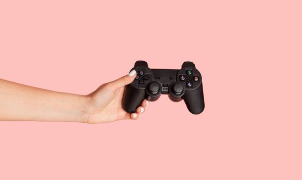 Getroffen weergave van jonge vrouw met video game joystick over roze achtergrond, close-up - Foto, afbeelding