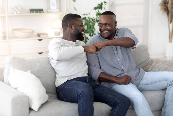 negro adulto hijo golpeando puños con su viejo padre en casa
 - Foto, Imagen