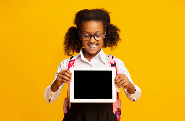 African American Schoolgirl Wyświetlanie Tablet Komputer pusty ekran, żółte tło - Zdjęcie, obraz