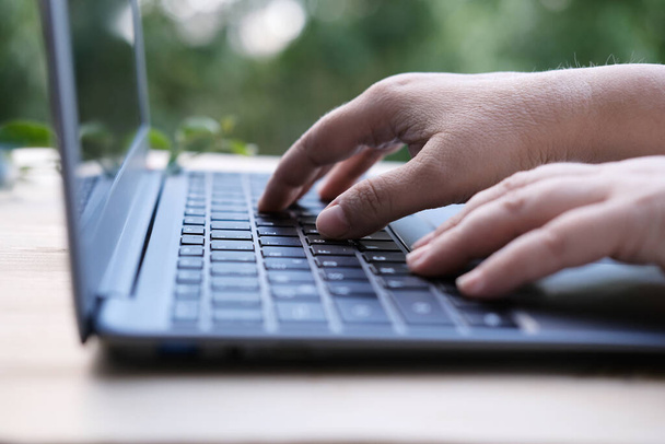 woman is typing on laptop keyboard, selective focus, working in evening at laptop of his house, hands closeup, concept of remote work, quarantine, downshifting - 写真・画像