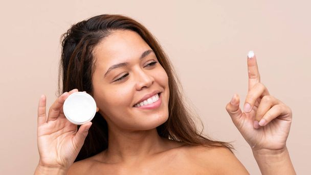 Young Brazilian girl with moisturizer over isolated background - Photo, Image