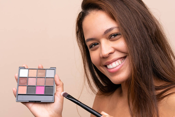 Young Brazilian girl with makeup palette over isolated background - Foto, Imagen