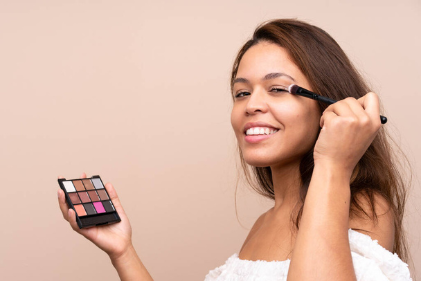 Chica brasileña joven con paleta de maquillaje sobre fondo aislado
 - Foto, imagen